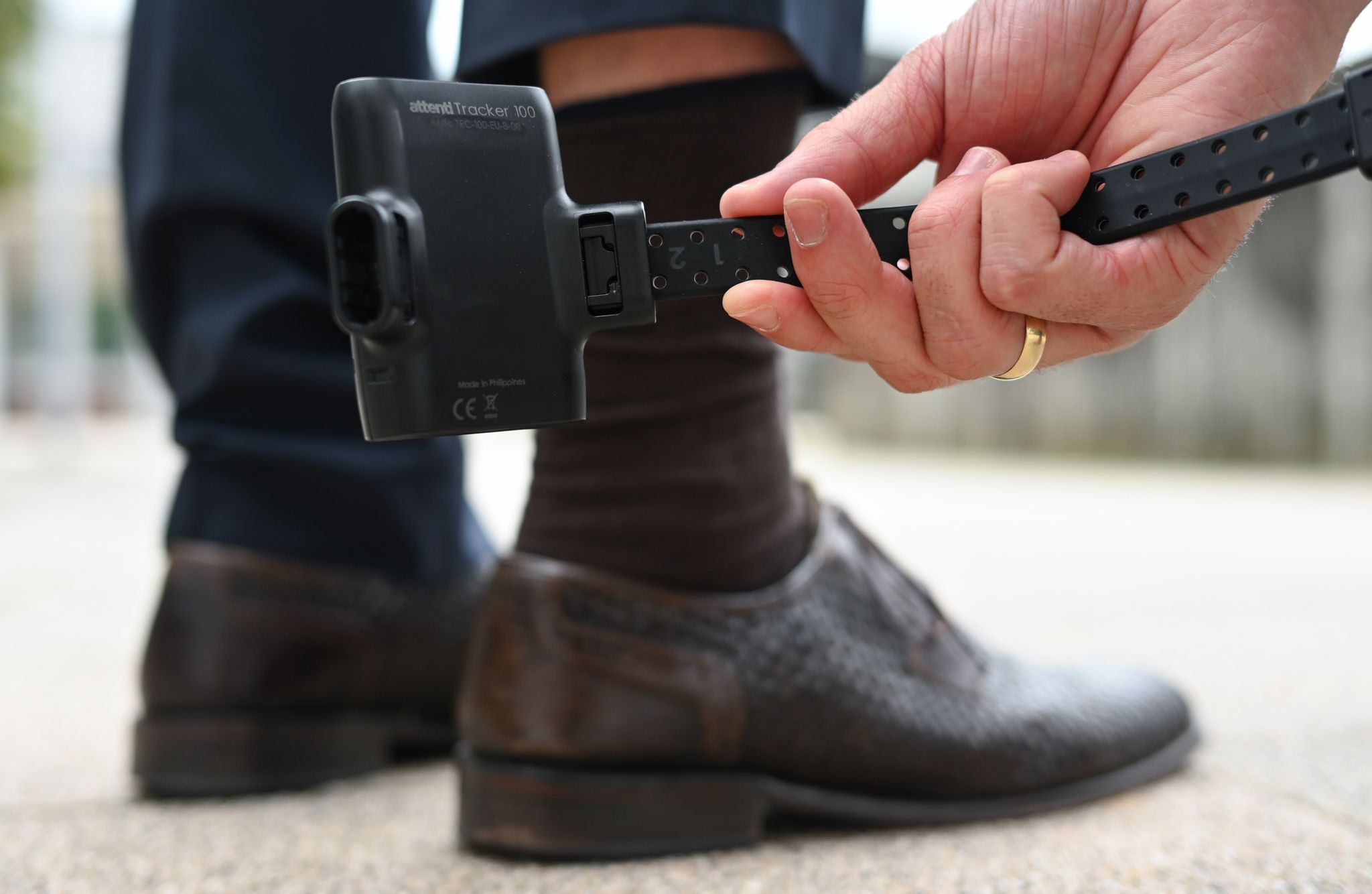 A man holds an electronic monitoring device, known as an electronic anklet, for demonstration purposes.