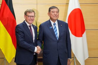 German Foreign Minister Johann Wadephul (L) and Japan's Prime Minister Shigeru Ishiba (R) greet each other before their talks.