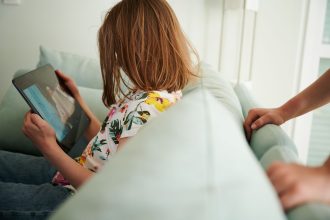 28 May 2022, Berlin: A child looks at a tablet. More than three-quarters of parents of teenage children in Germany are stressed, a survey found on Tuesday.