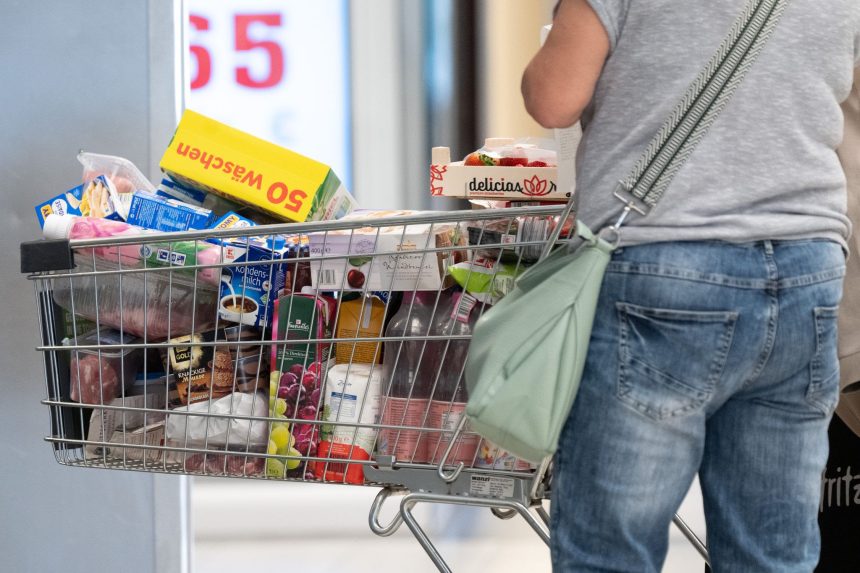 A person stands next to a full shopping cart.