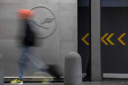 29 September 2025, Hesse, Frankfurt/Main: A man walks in front of a Lufthansa logo at Frankfurt Airport. Company sources have revealed that the Group intends to cut a fifth of its administrative jobs in the coming years. The Executive Board intends to present its comprehensive plans for staff cuts in more detail this Monday. Photo: Hannes P. Albert/dpa