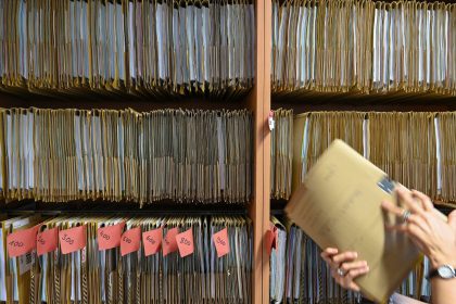 An employee of a public authority reaches for a file on a shelf. Photo: Arne Dedert/dpa