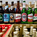13 October 2015, Bavaria, Nuremberg: Beer bottles of the Anheuser-Busch Inbev group of the brands (L-R) Corona, Diebels, Loewenbraeu, Franziskaner, Hasseroeder, Beck's and Budweiser stand next to bottles of the Pilsner Urquell and Tyskie brands of the SABMiller group in Nuremberg. Decades after a legal dispute over the beer brands Bud and Bit, the world's largest brewing group, AB InBev, is bringing its lager beer back to the German market under the name Anheuser-Busch Bud. Photo: picture alliance / Daniel Karmann/dpa