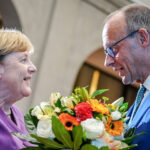 25 September 2024, Berlin: Then Christian Democratic Union of Germany (CDU) federal chairman Friedrich Merz presents Former German Chancellor Angela Merkel with a bouquet of flowers at a special Berlin discussion to mark the former Chancellor's 70th birthday. A party organized by the parliamentary faction of German Chancellor Friedrich Merz to mark his 70th birthday will take place without his predecessor Angela Merkel. Photo: Kay Nietfeld/dpa