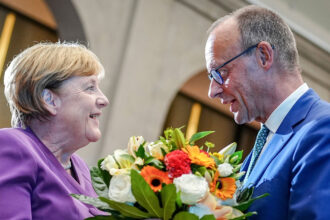25 September 2024, Berlin: Then Christian Democratic Union of Germany (CDU) federal chairman Friedrich Merz presents Former German Chancellor Angela Merkel with a bouquet of flowers at a special Berlin discussion to mark the former Chancellor's 70th birthday. A party organized by the parliamentary faction of German Chancellor Friedrich Merz to mark his 70th birthday will take place without his predecessor Angela Merkel. Photo: Kay Nietfeld/dpa