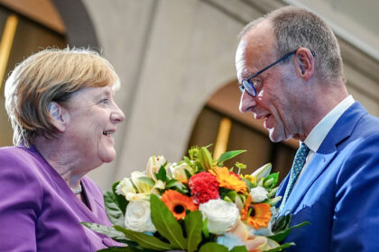 25 September 2024, Berlin: Then Christian Democratic Union of Germany (CDU) federal chairman Friedrich Merz presents Former German Chancellor Angela Merkel with a bouquet of flowers at a special Berlin discussion to mark the former Chancellor's 70th birthday. A party organized by the parliamentary faction of German Chancellor Friedrich Merz to mark his 70th birthday will take place without his predecessor Angela Merkel. Photo: Kay Nietfeld/dpa
