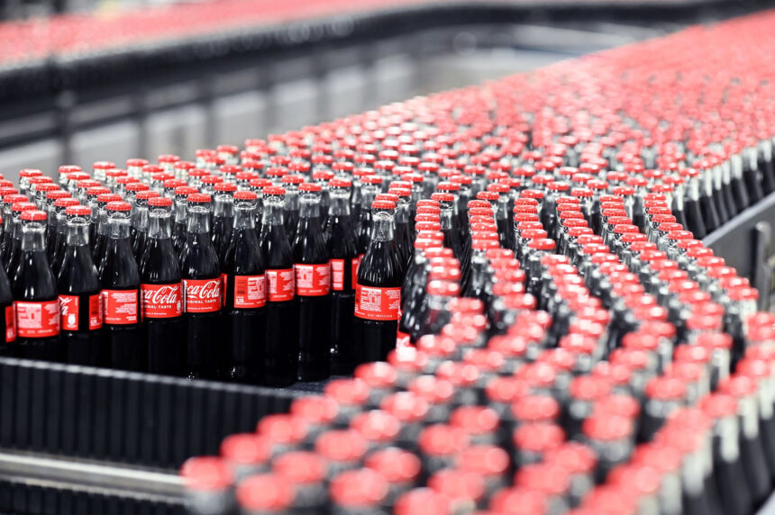 Coca-Cola glass bottles are transported on a conveyor belt at the Mannheim production site of Coca-Cola Europacific Partners - CCEP Deutschland GmbH. Photo: Uli Deck/dpa