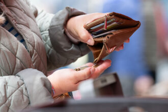 A woman holds an open wallet at a weekly market. Photo: Sebastian Kahnert/dpa