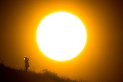 A walker stands in front of the setting sun near Hanover in northern Germany. Photo: Julian Stratenschulte/dpa