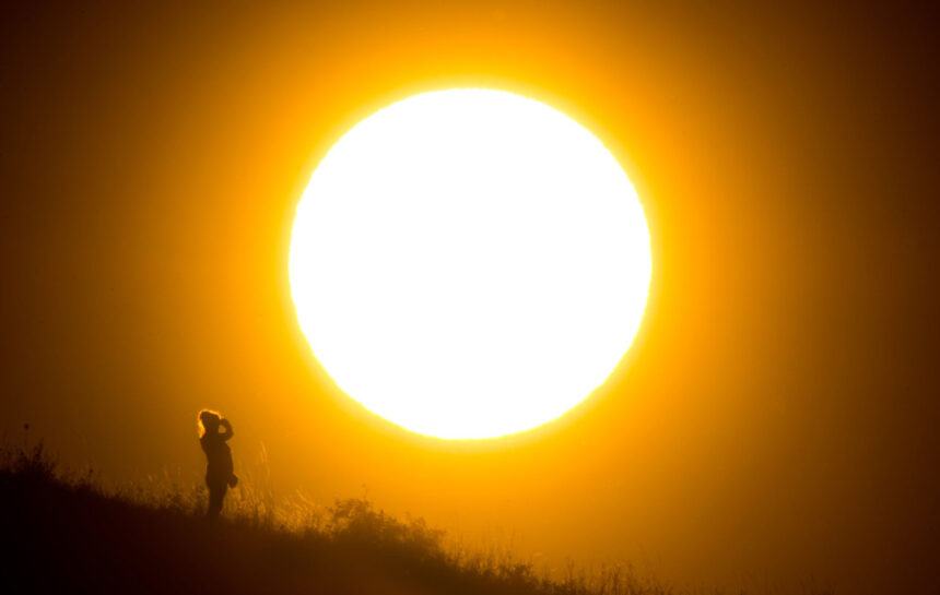 A walker stands in front of the setting sun near Hanover in northern Germany. Photo: Julian Stratenschulte/dpa