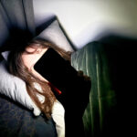 File Photo - A woman lies on a bed and holds a smartphone in front of her face. Photo: Alicia Windzio/-/dpa