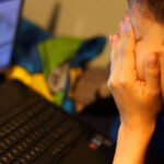 ARCHIVE - ILLUSTRATION - A boy sits in front of his laptop, rubbing his eyes in frustration. Photo: Oliver Berg/dpa
