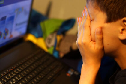 ARCHIVE - ILLUSTRATION - A boy sits in front of his laptop, rubbing his eyes in frustration. Photo: Oliver Berg/dpa