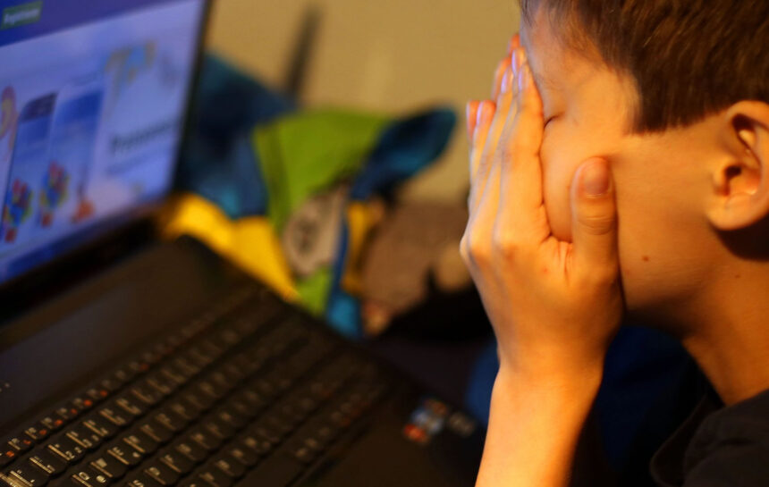 ARCHIVE - ILLUSTRATION - A boy sits in front of his laptop, rubbing his eyes in frustration. Photo: Oliver Berg/dpa